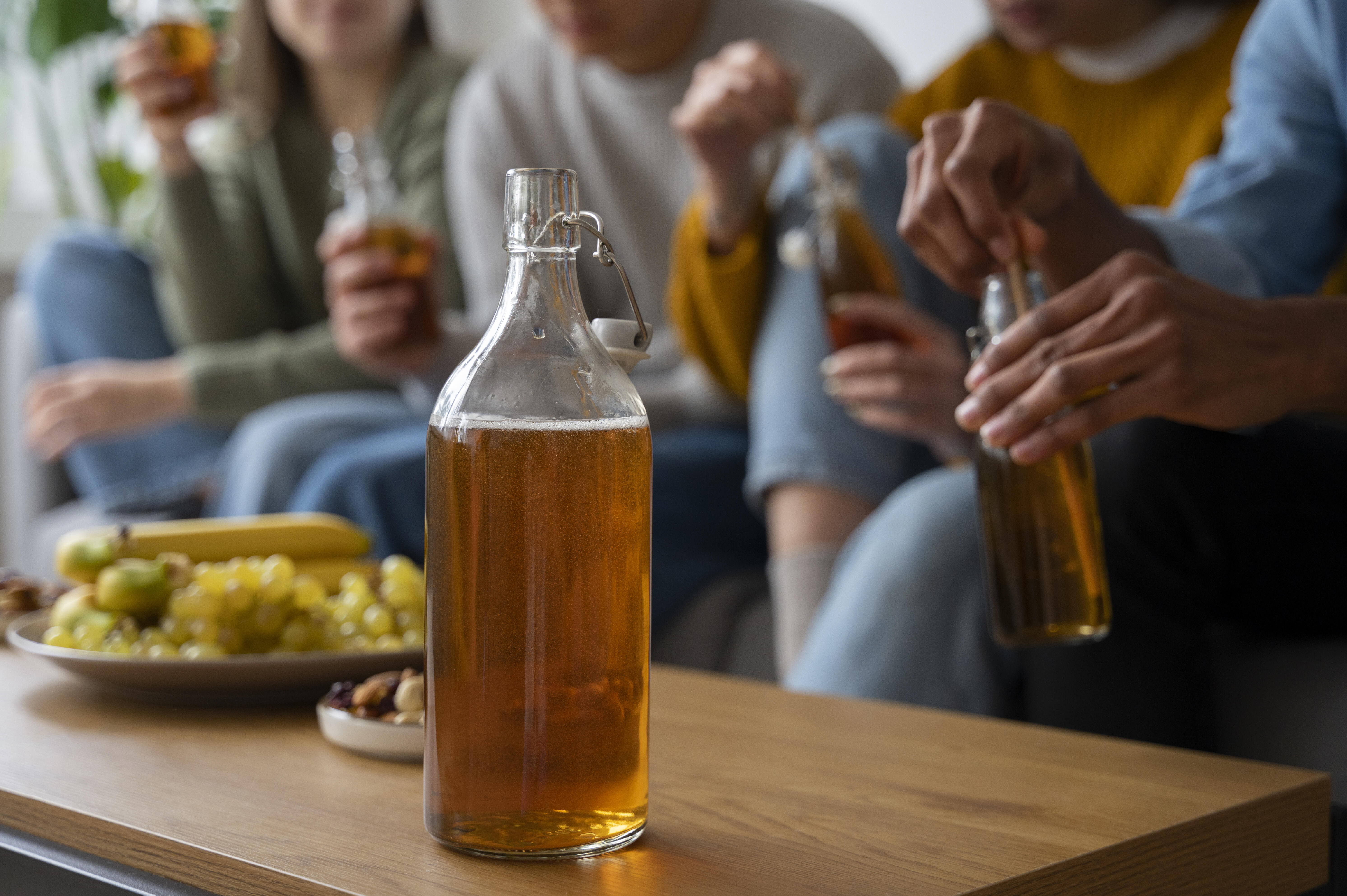 cider fermentation, people trying homemade cider in a glass bottle