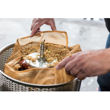 Fruit pomace in straining bag inside steel pressing cage.