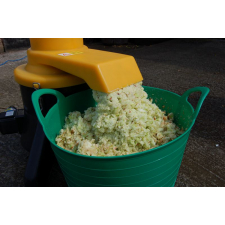 Fresh apple pomace pouring from Speidel Mill into green tub.