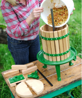 Woman pouring crushed apples into fruit press.