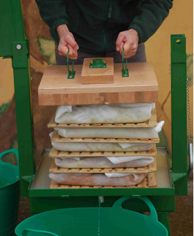 Man fitting pressing block to pomace cheese.